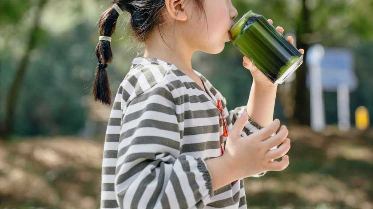 Little girl drinking soda from can on a sunny day outdoors in the park