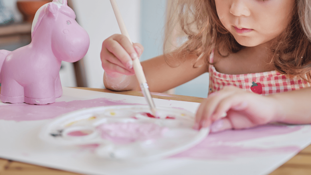 little girl painting unicorn toy