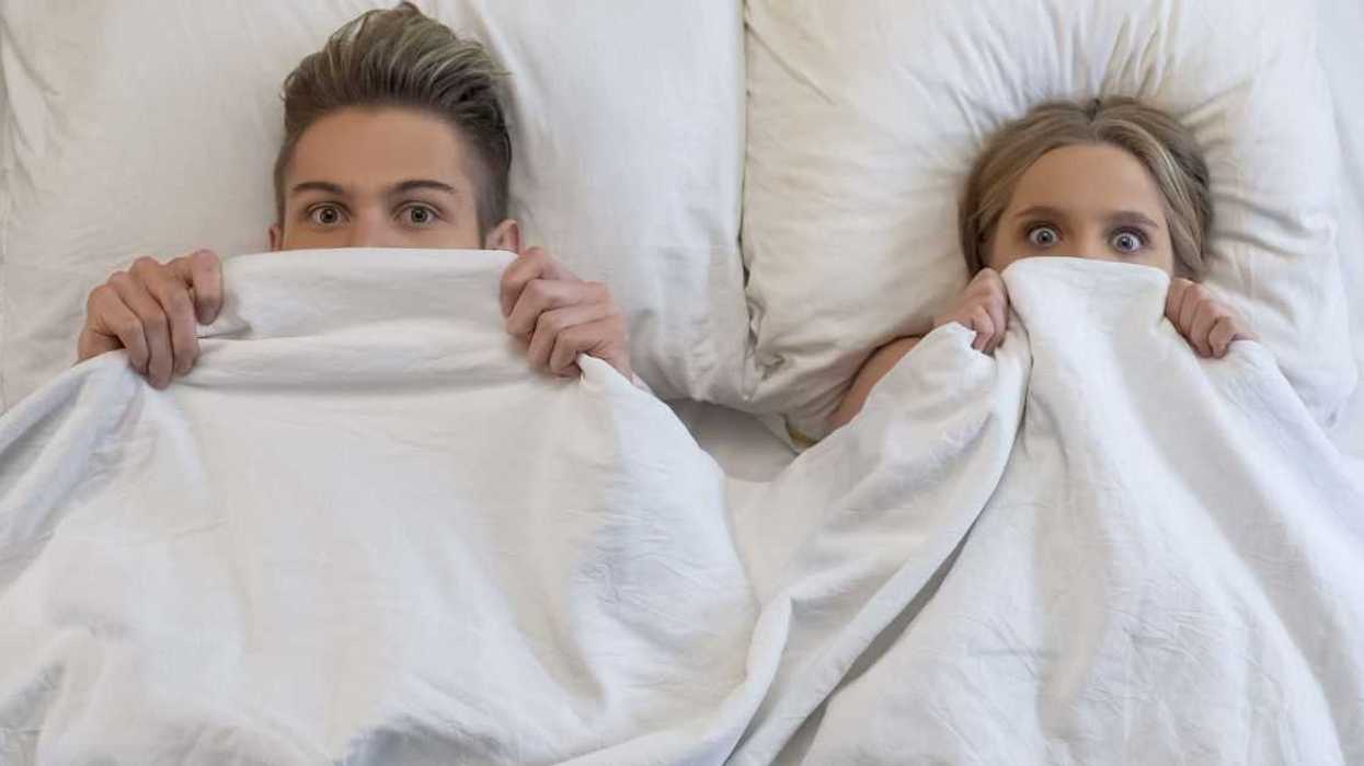 Lovers caught in bed by parents, embarrassed and frightened, looking shocked.