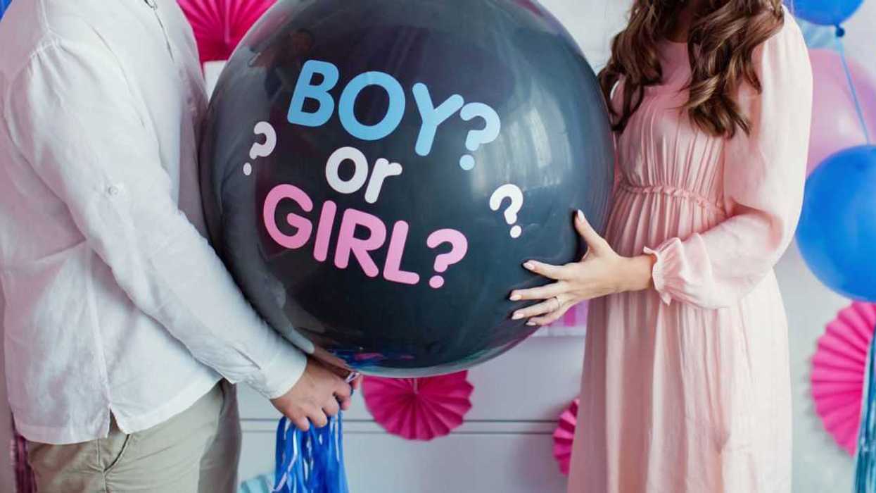 Man and woman holding black balloon with "boy or girl?" on gender reveal party.