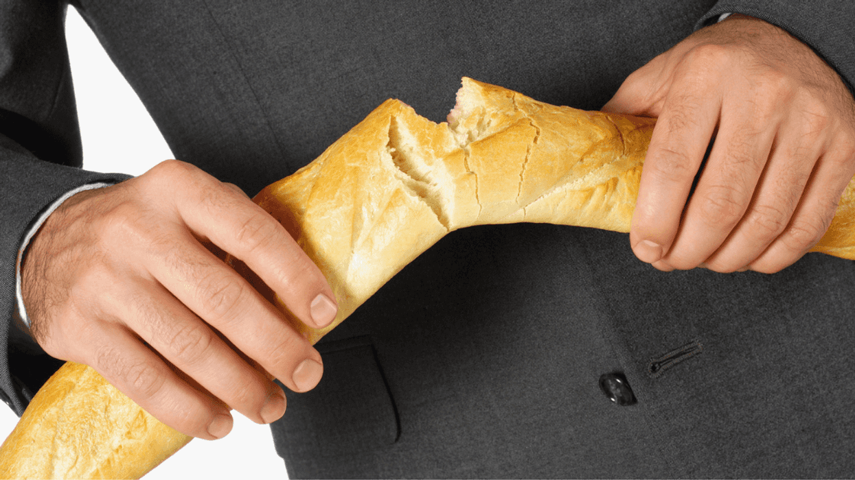 man breaking baguette in half