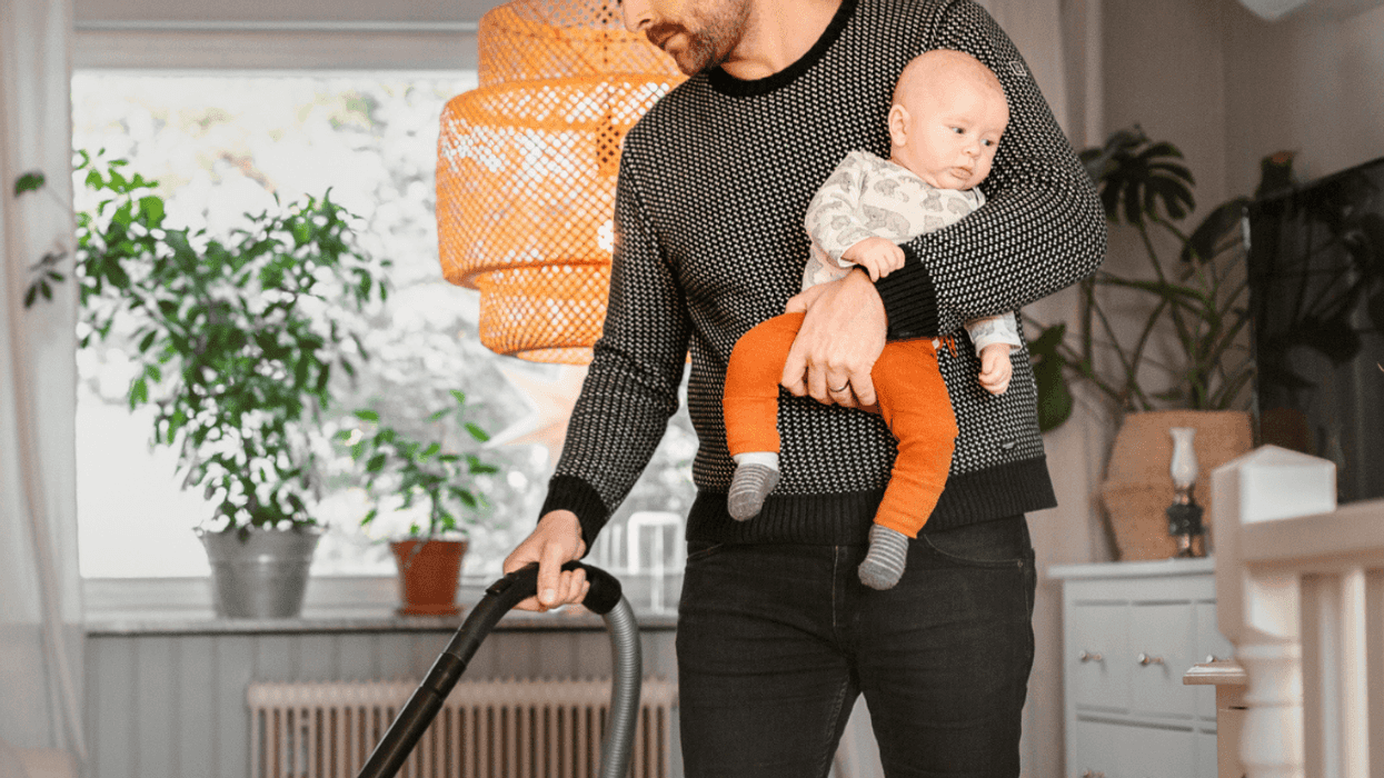 Man cleaning home while holding baby