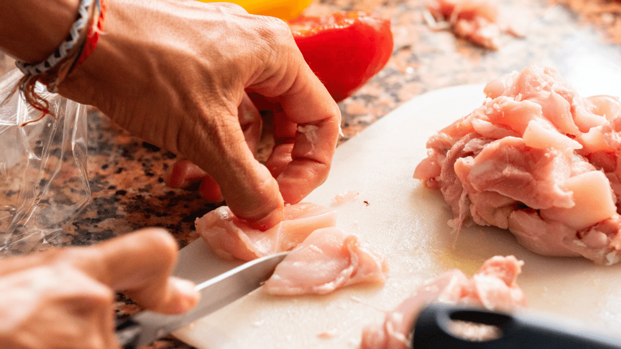 man cutting up chicken breasts