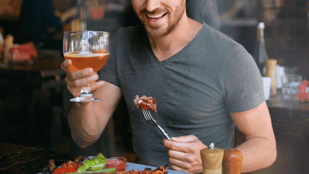 man drinking beer and eating steak
