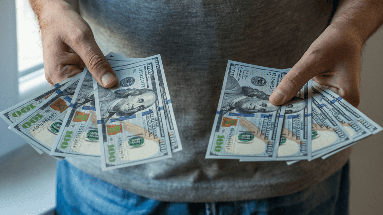 man holding fanned out $100 bills