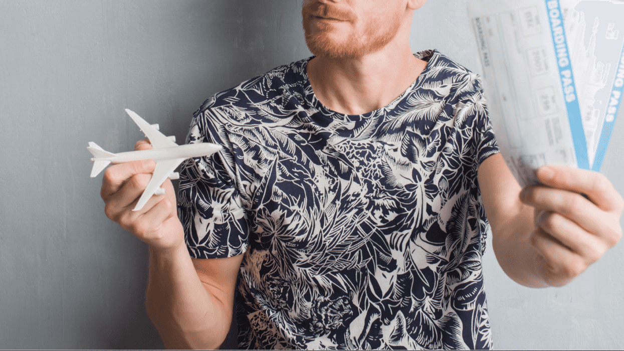 Man holding miniature airplane and airline tickets.