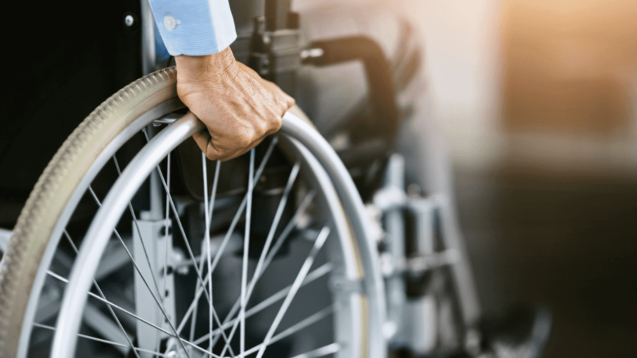 Man holding onto the wheels of a wheelchair.