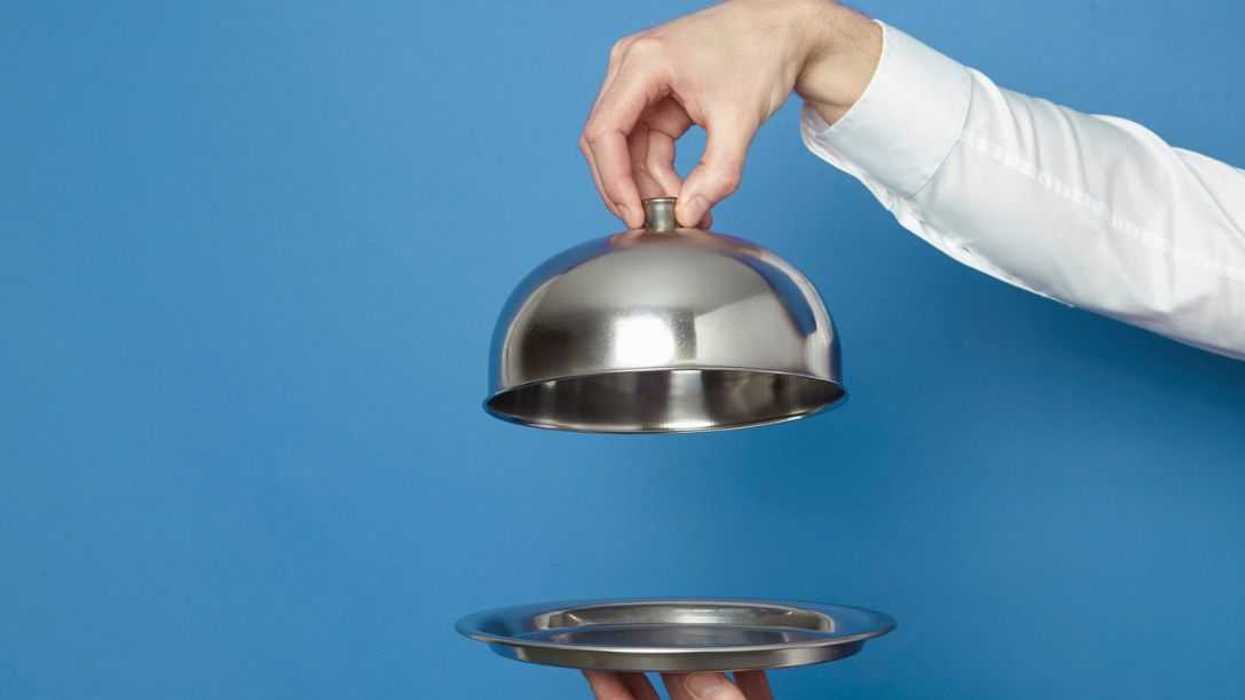Man holding silver tray and lid against blue and green background.