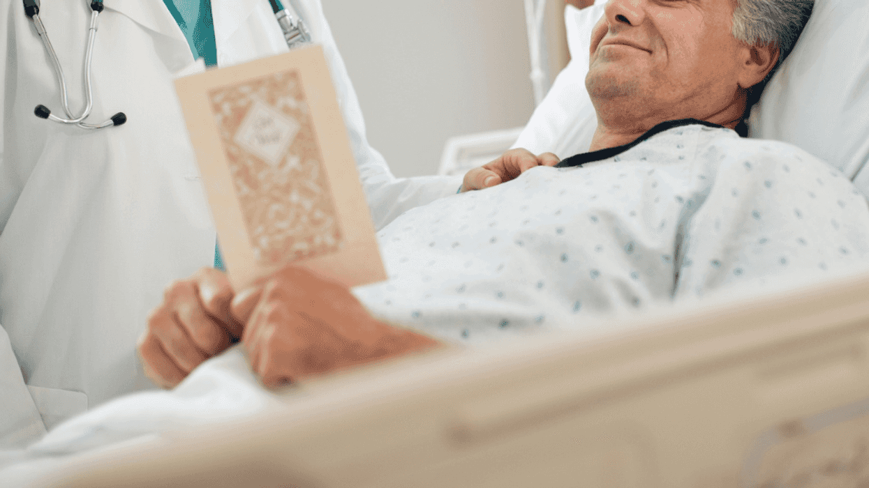 man in hospital bed looks at Get Well card with doctor