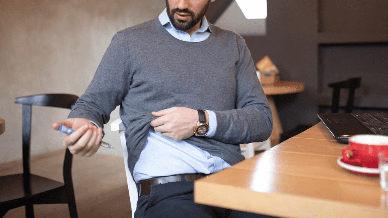 man injecting insulin while seated at a table