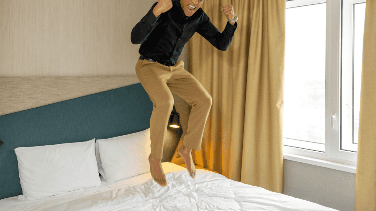 Man jumping in the bed while in clothes