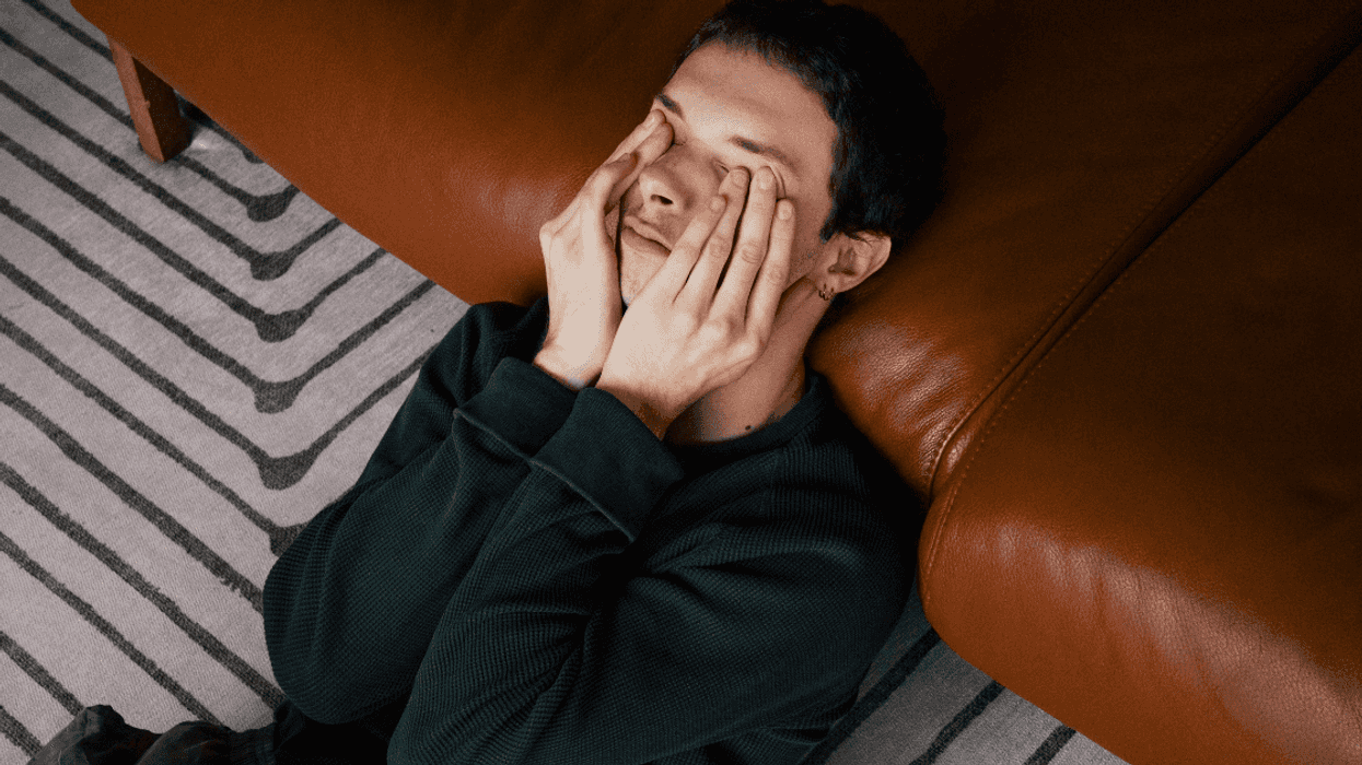 man laying on floor with hands over eyes
