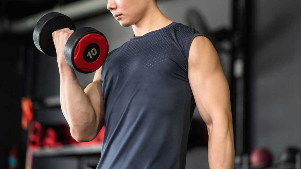 Man lifting dumbbells to build arm muscles in gym.