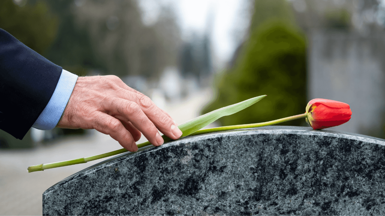 Man placing flower on tombstone
