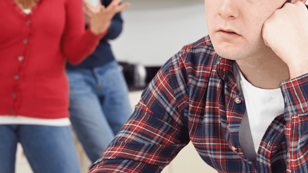 Man resting his head in his hands with a frustrated couple behind him.