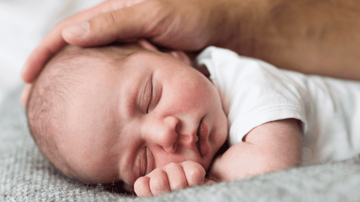 man's hand resting on baby's head