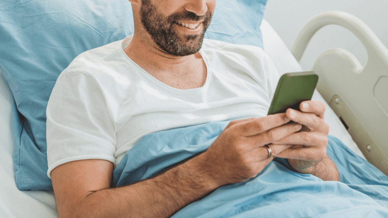 Man scrolling through his phone in a hospital bed