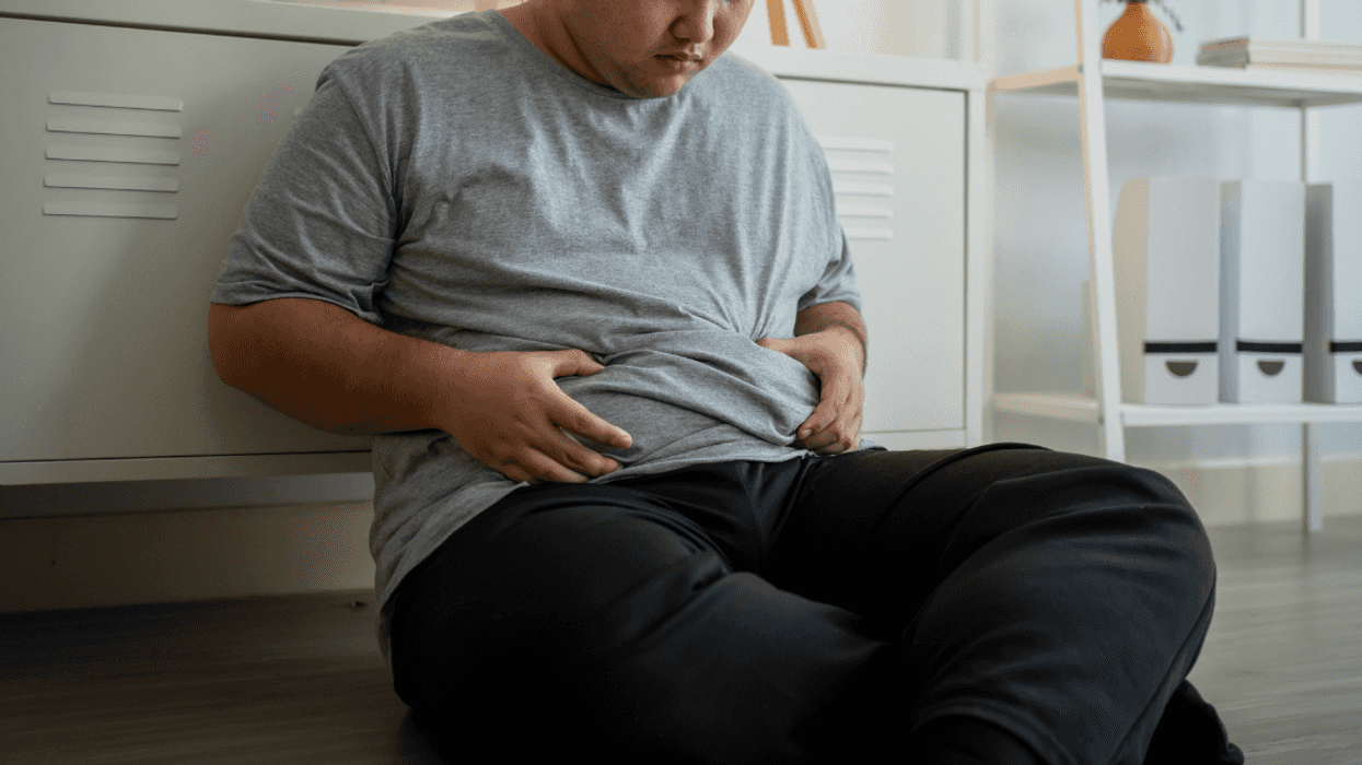 man seated on floor gripping his midsection