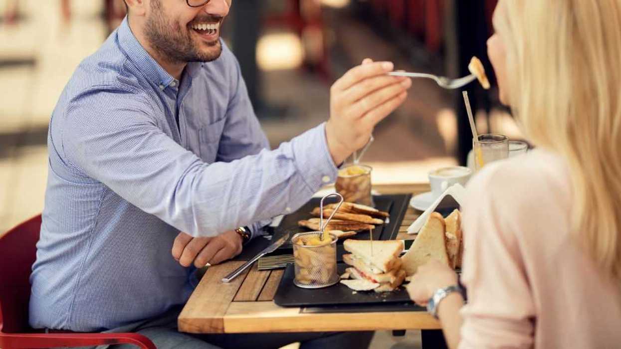 Man sharing his food and feeding his girlfriend.