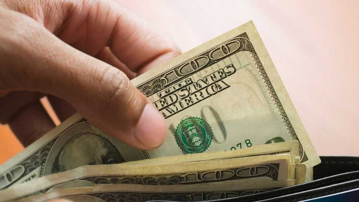 Man taking hundred bills out of wallet.