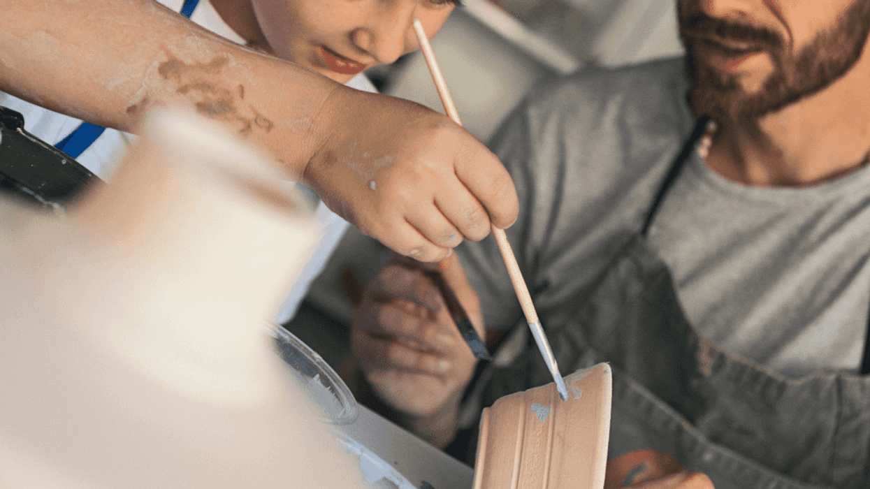 Man teaching boy how to paint