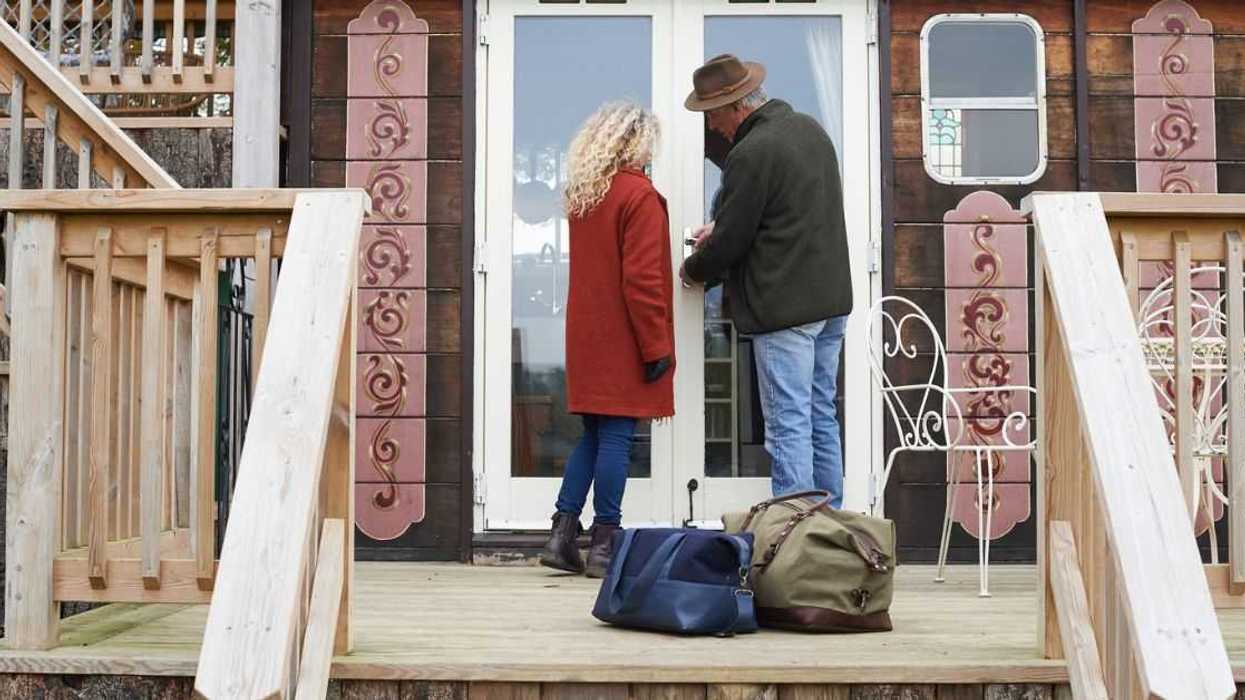 Mature couple arriving for a glamping weekend at an eco lodge.They are unlocking the door on arrival.