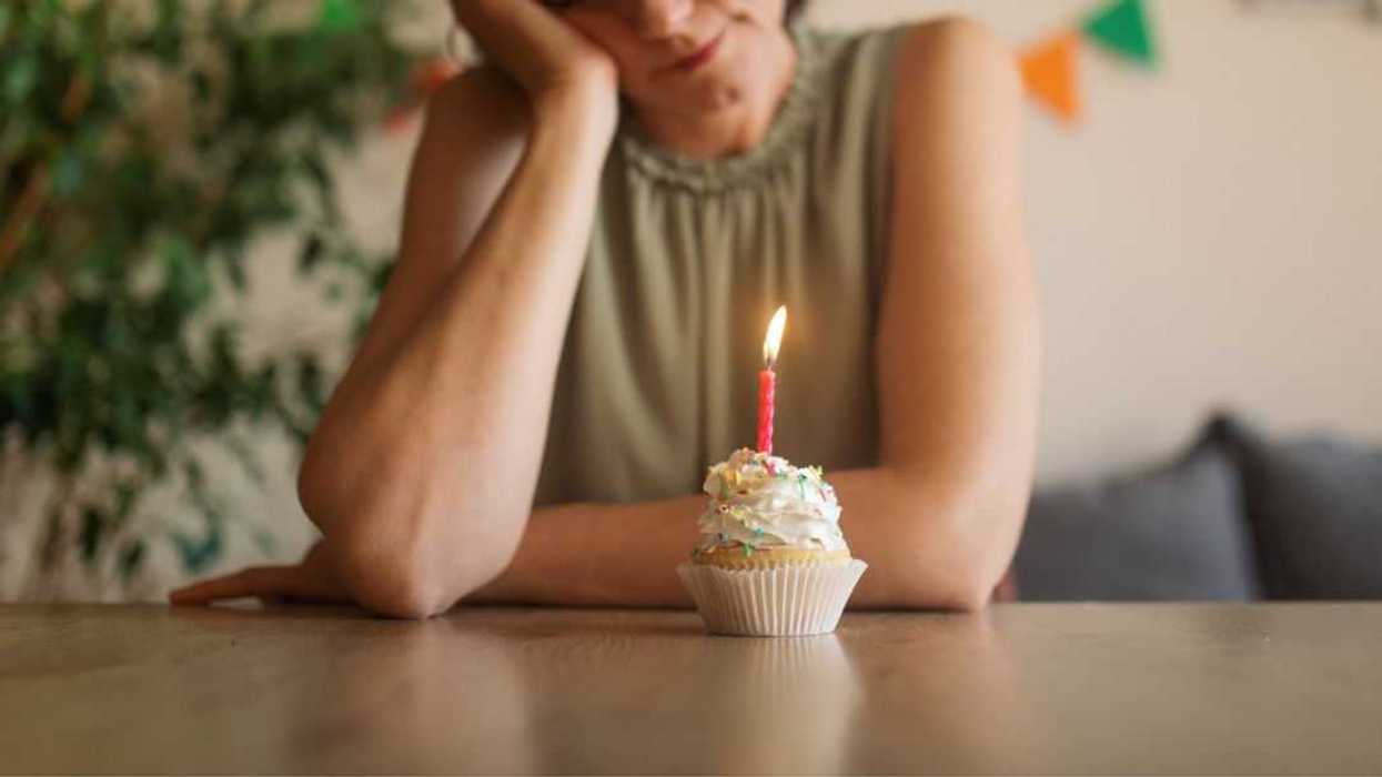 Mature woman celebrating her birthday alone at home. She looks unhappy and depressed.