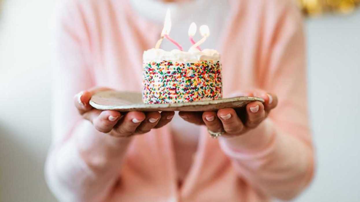 Midsection shot of a woman holding cake with burning birthday candles.