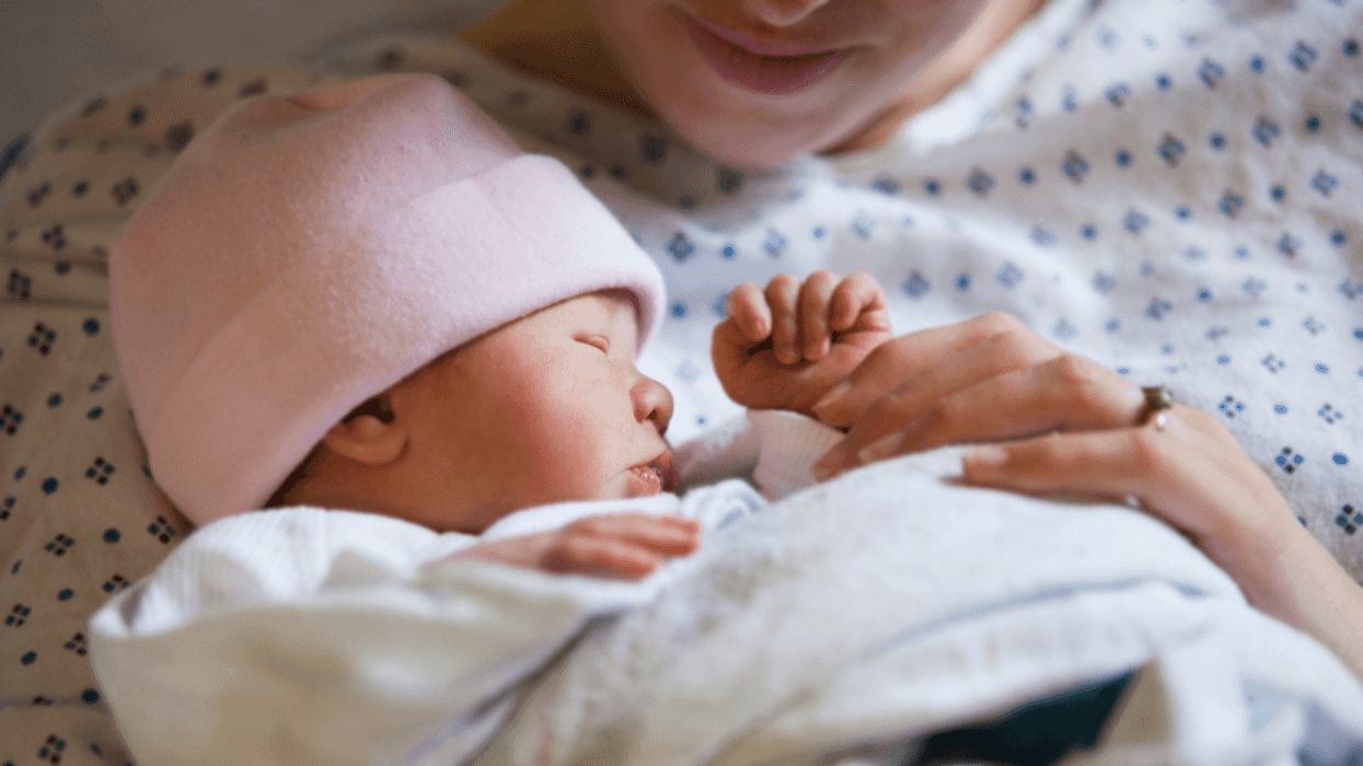 mother holding newborn baby in hospital bed