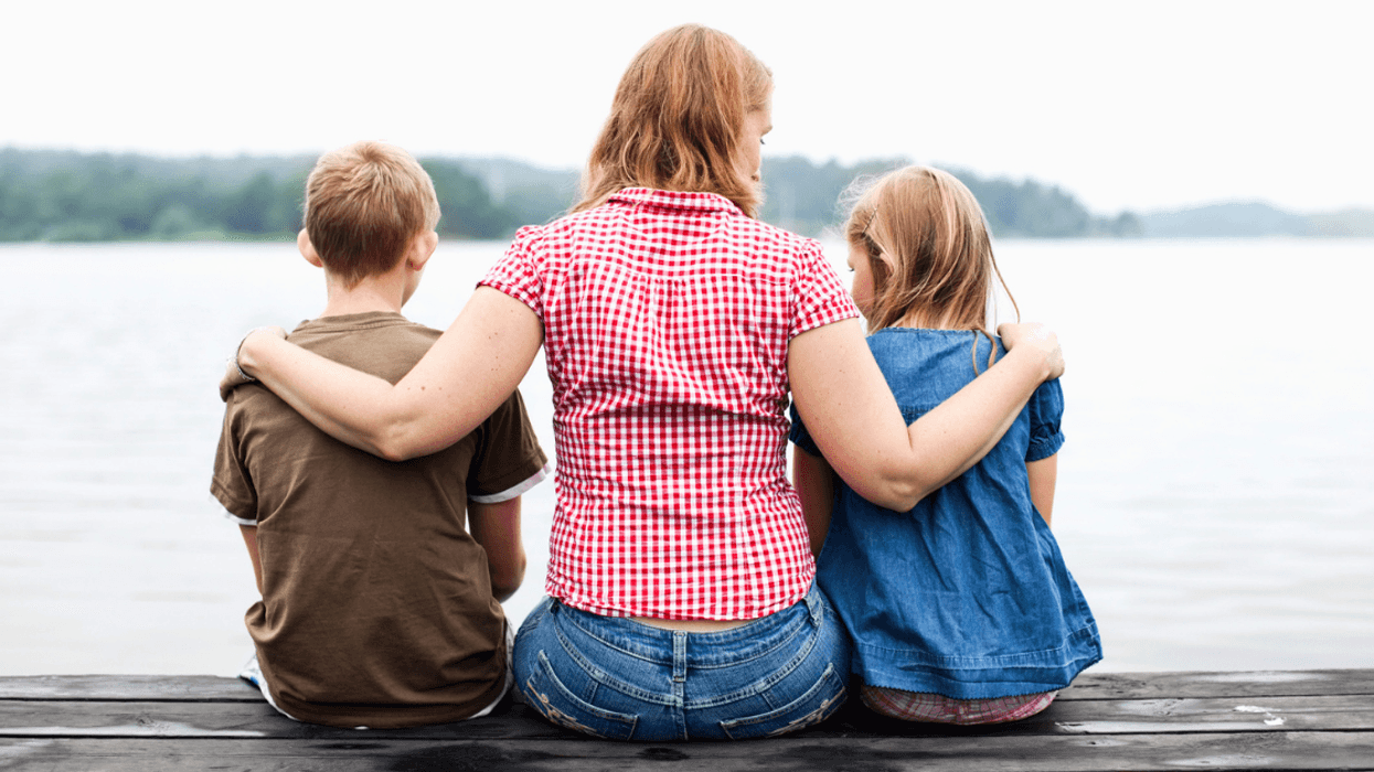 mother seated on dock between two children