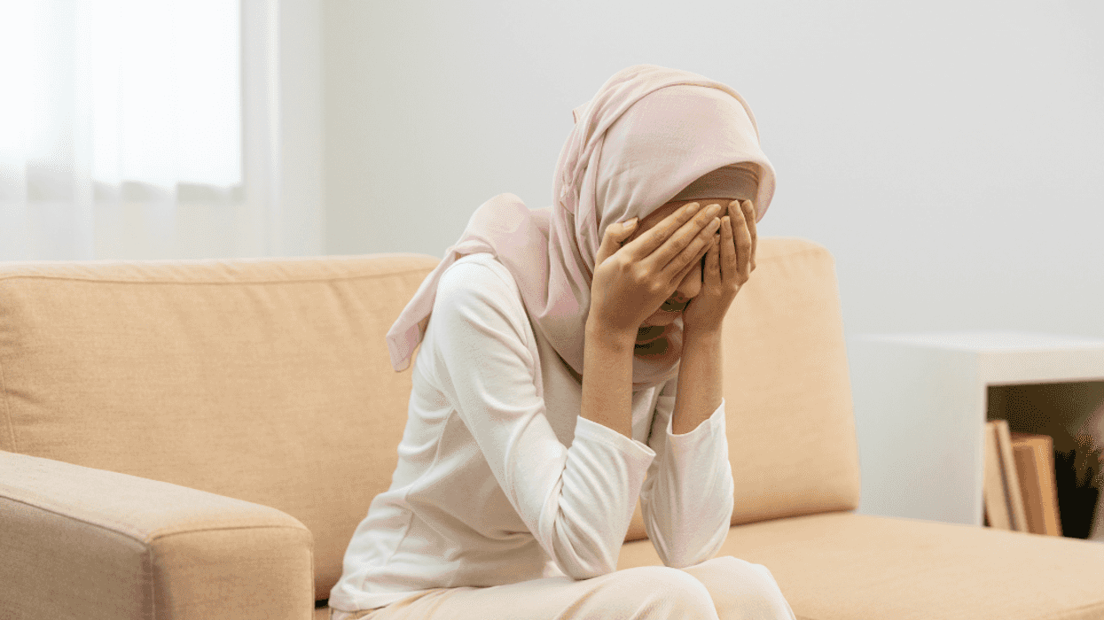 Muslim woman with her face in her hands