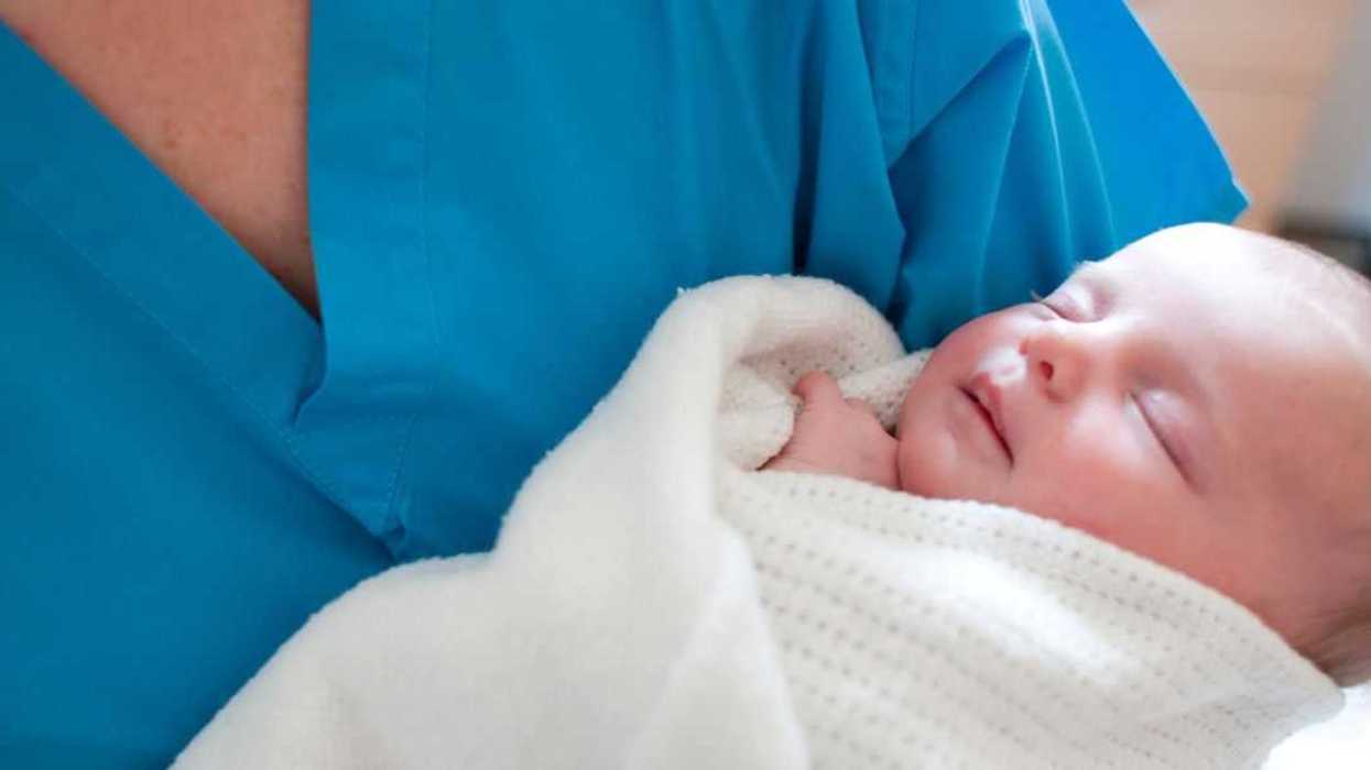 Newborn baby held by a nurse.