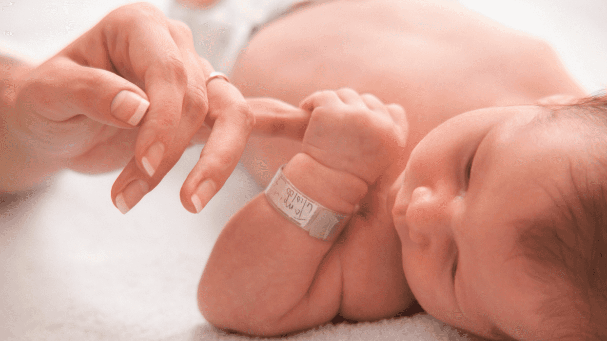 newborn infant holding an adult's finger