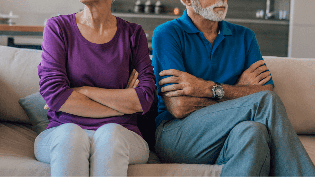 Older couple sitting angrily on a sofa.