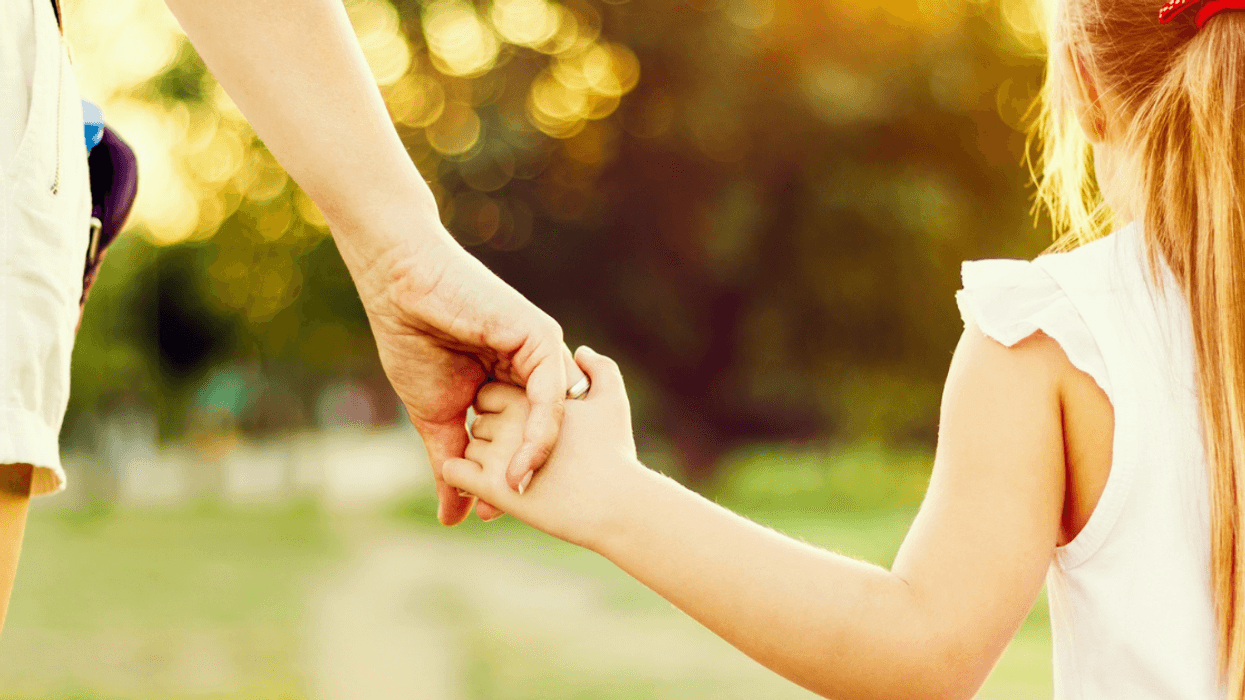 older female holding female child's hand