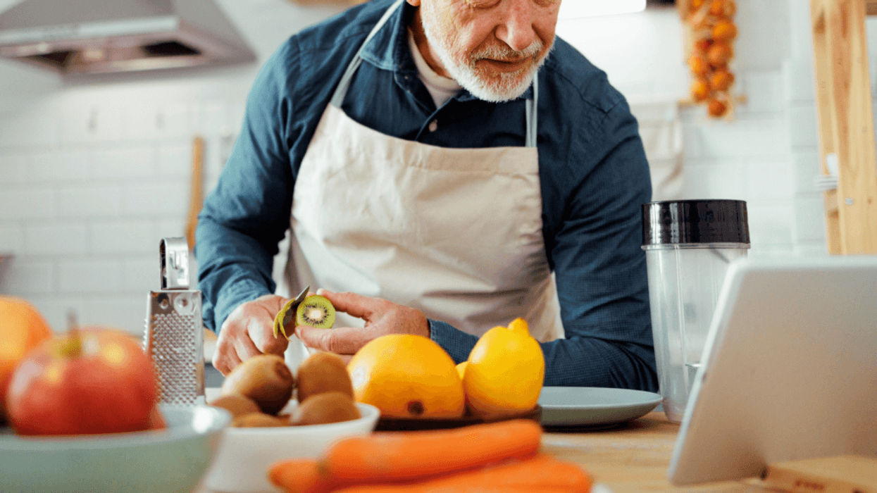 older man cooking while following a recipe on a tablet