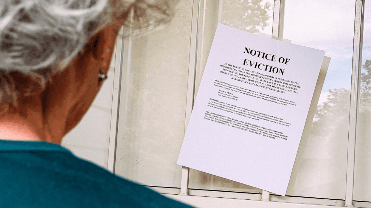 older woman looking at eviction notice posted on door