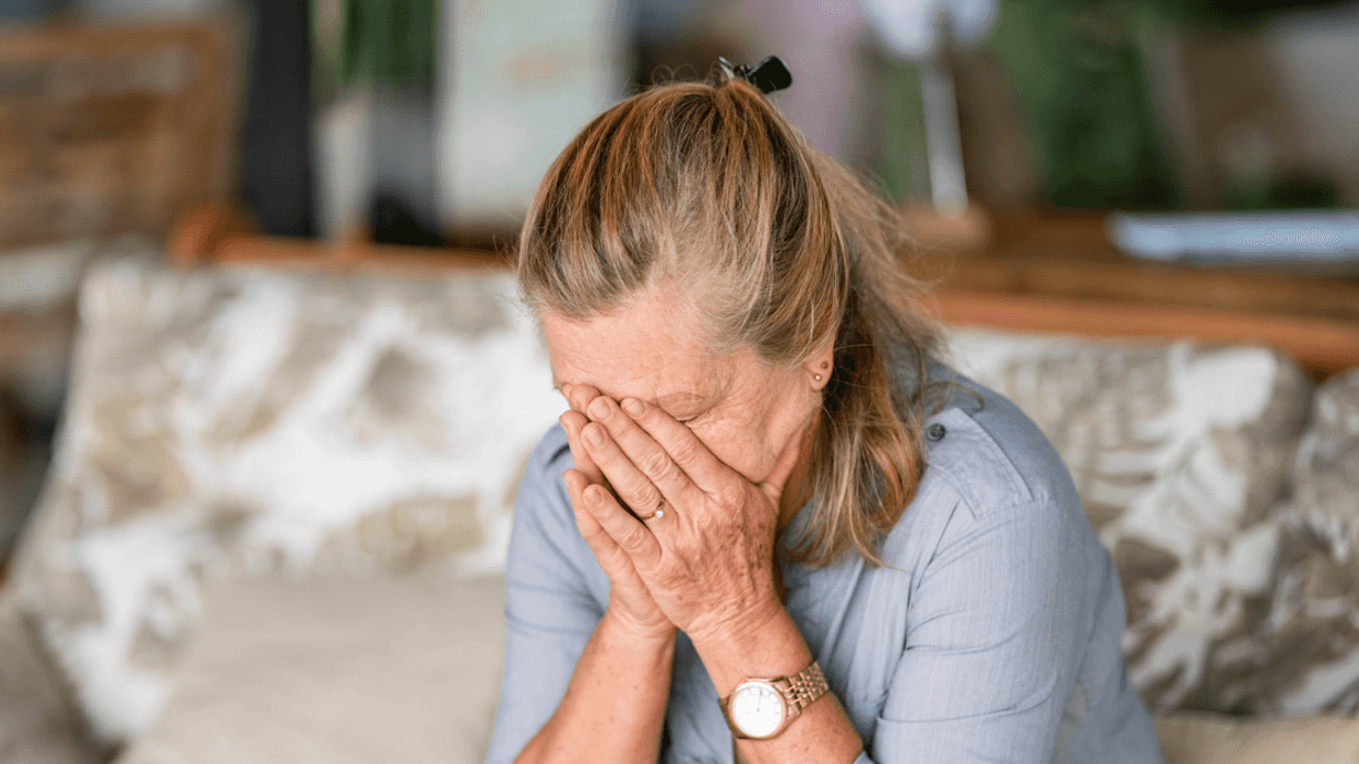 older woman on couch with head in hands