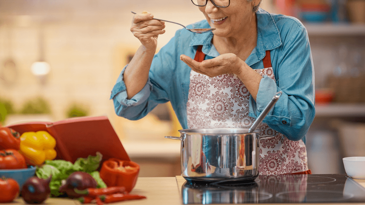 older woman tasting sauce cooking in dutch oven