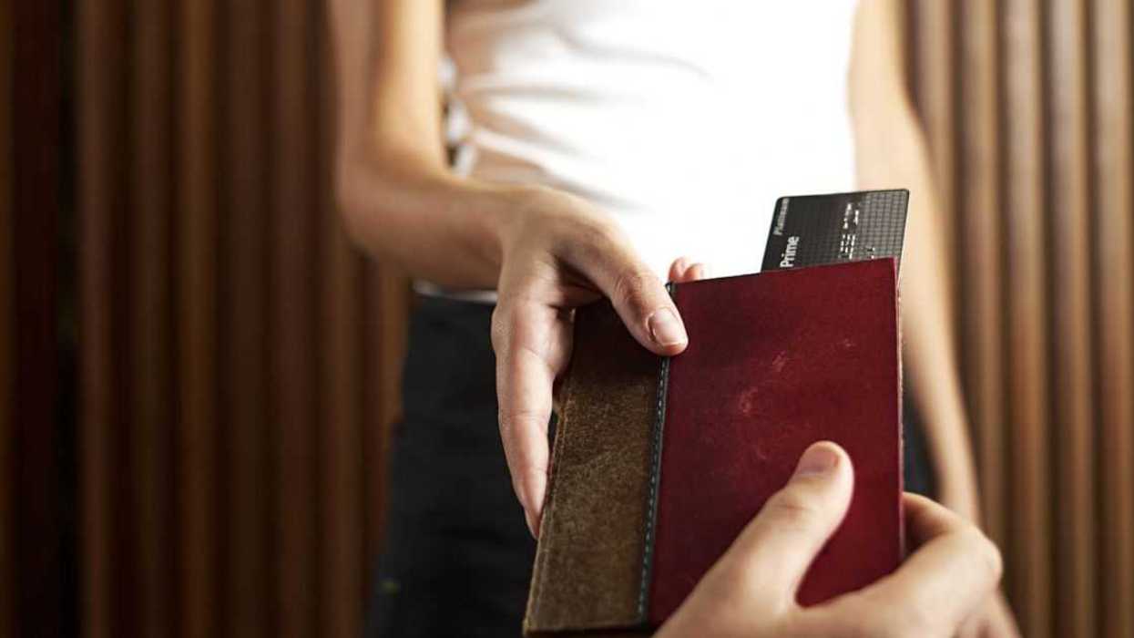 One hand gives a billfold with a credit card to another hand