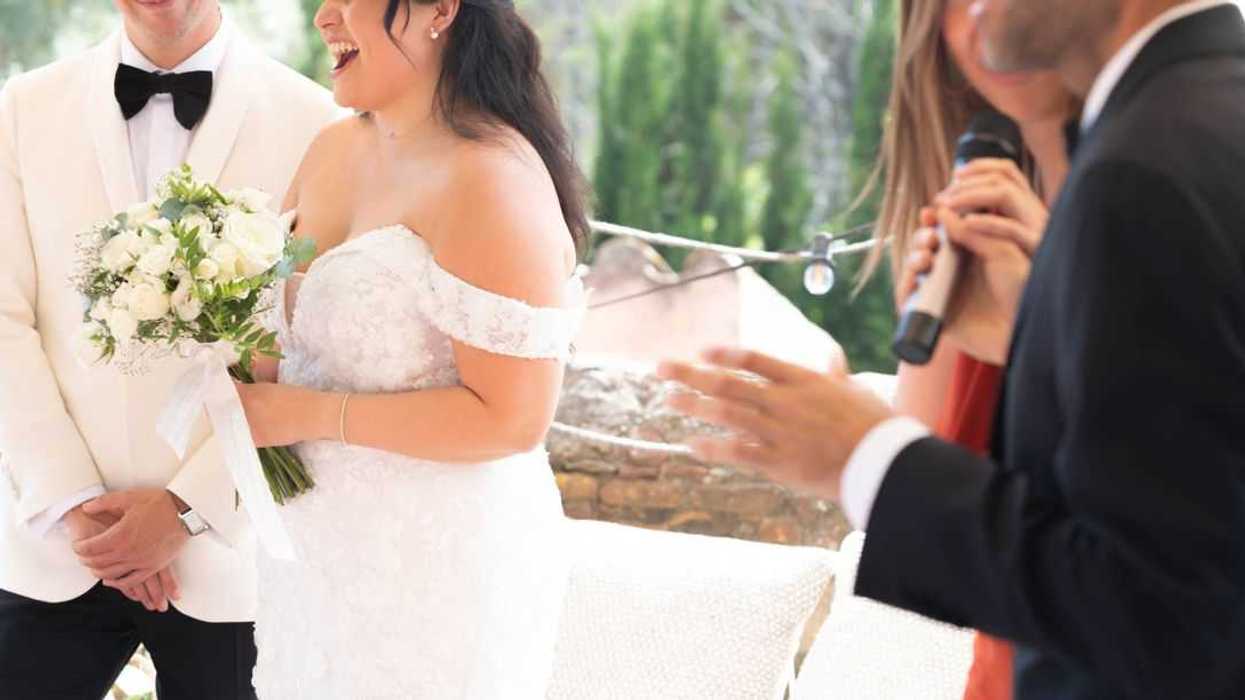 Outdoor wedding ceremony with bride and groom laughing as master of ceremony and guests deliver funny speeches.