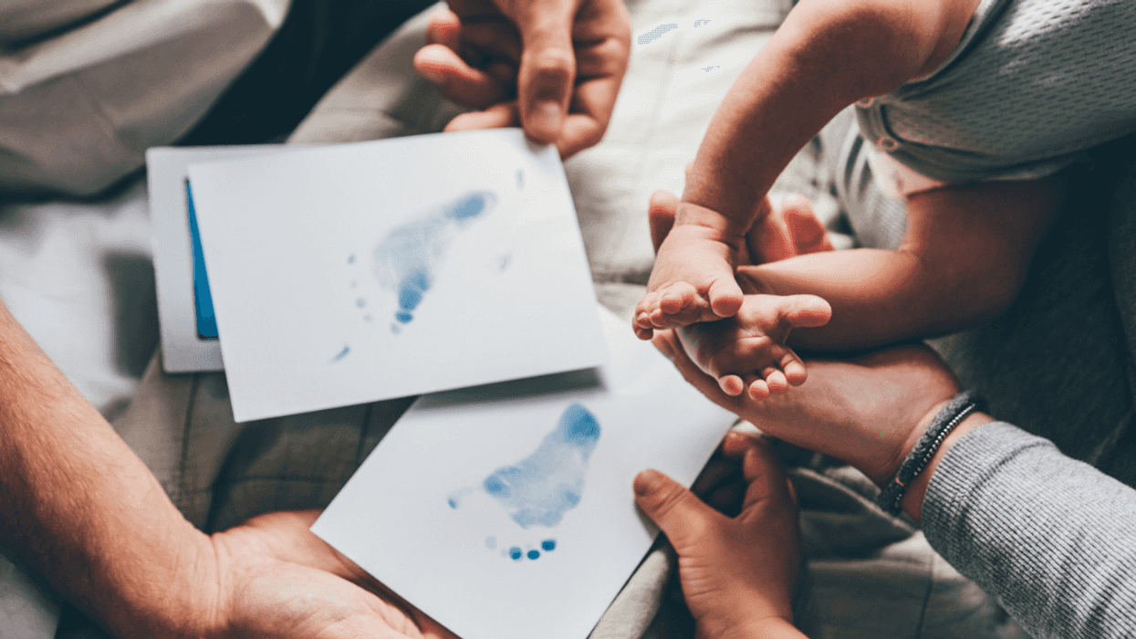 Parents helping their baby take ink footprints