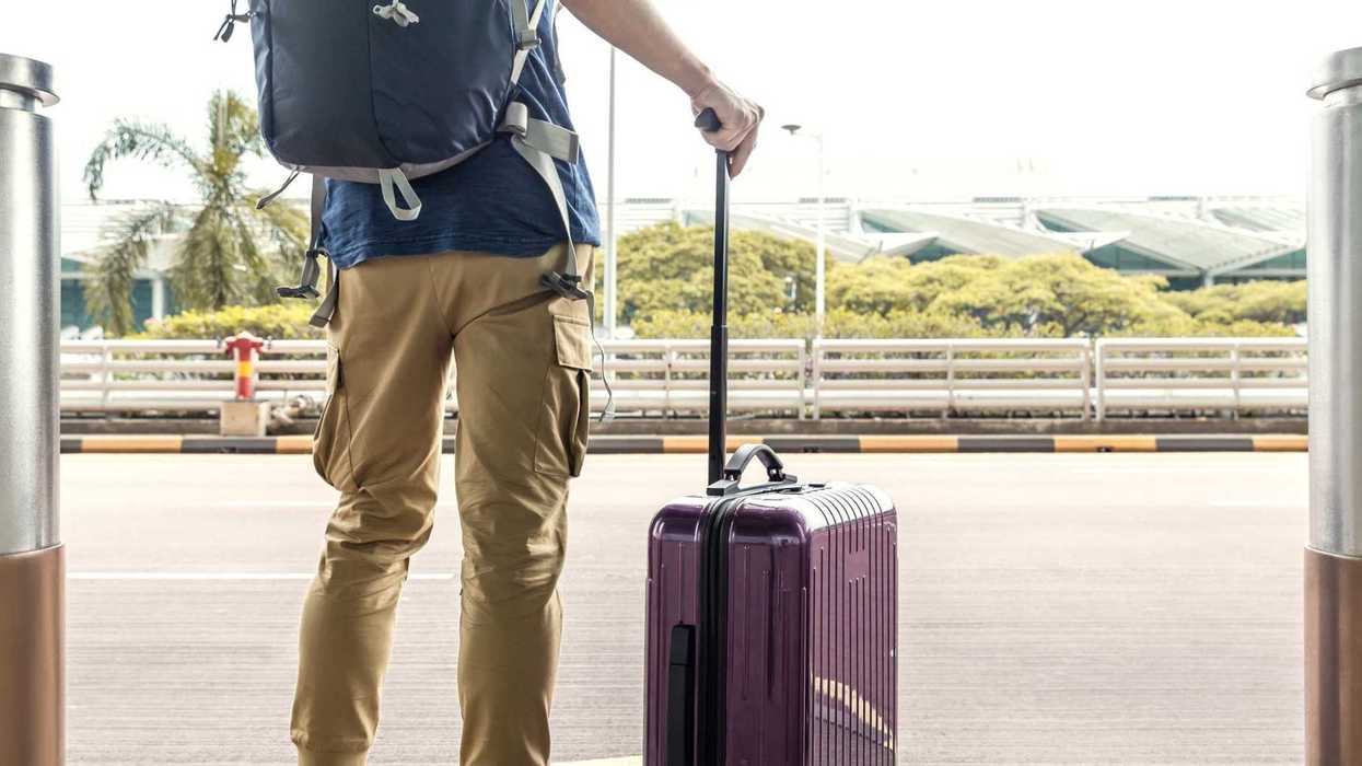 Passengers with luggage are waiting for a taxi at the airport.