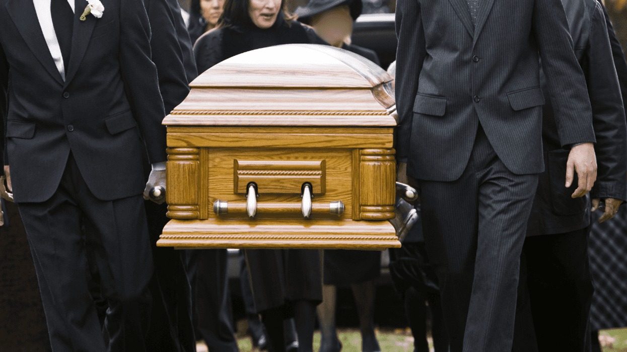 people carrying casket to grave at cemetery