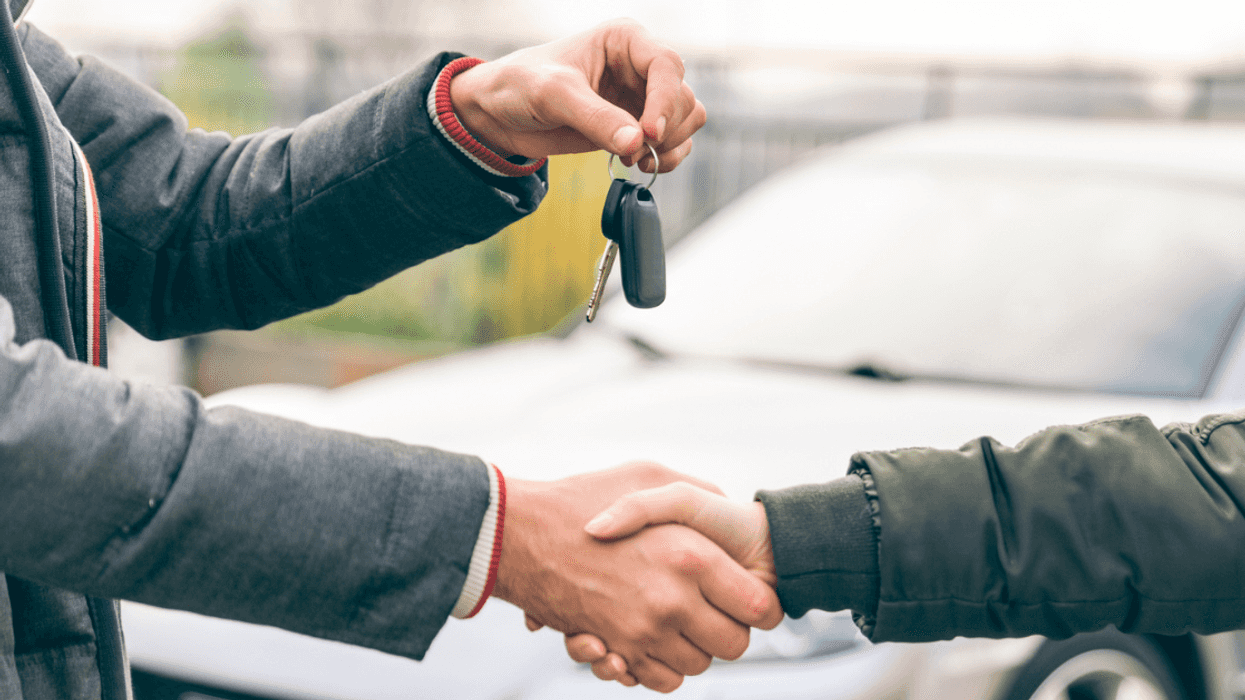 people shaking hands and exchanging car keys