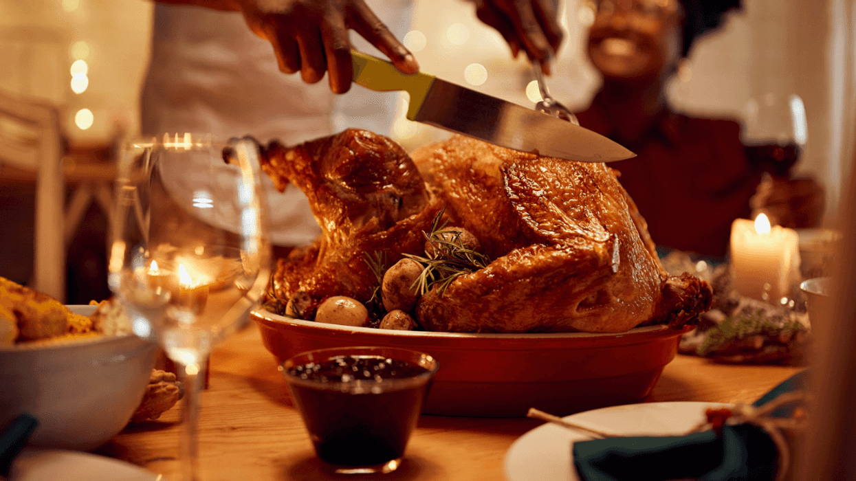 person carving turkey at dinner table