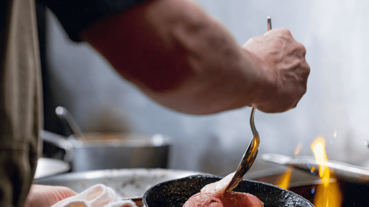 person cooking meat with butter