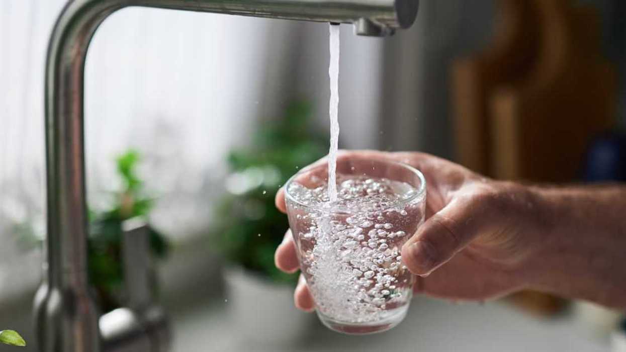 Person filling glass of water from kitchen sink