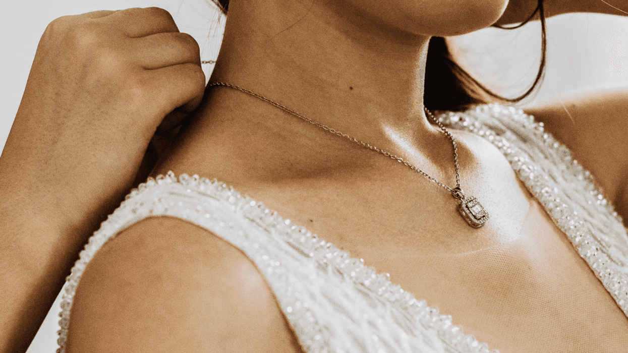 person helping bride put on antique necklace