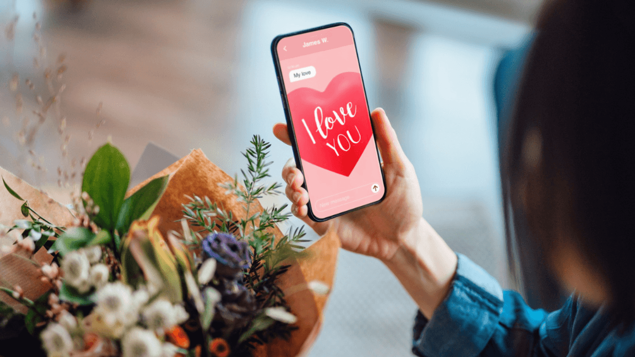 person holding bouquet while looking at phone screen that says "I love you"